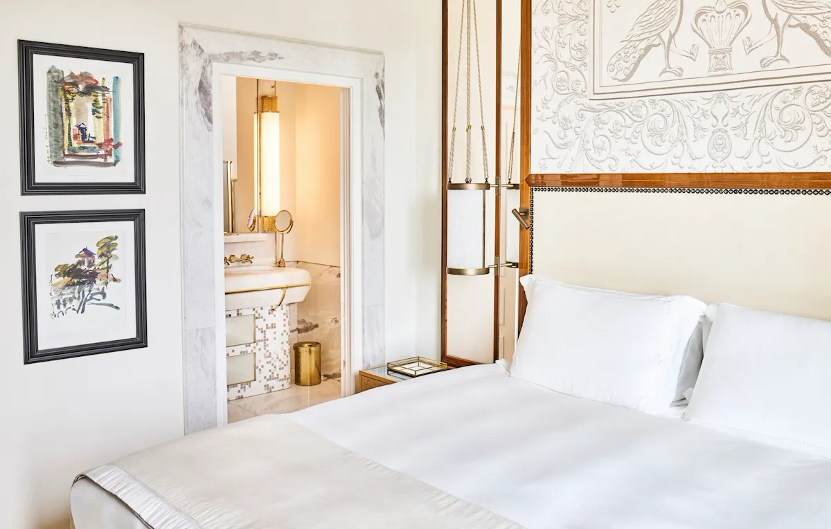 Bedroom of Classic suite with view with paintings on the wall and bathroom in the background at Hotel Eden, Rome