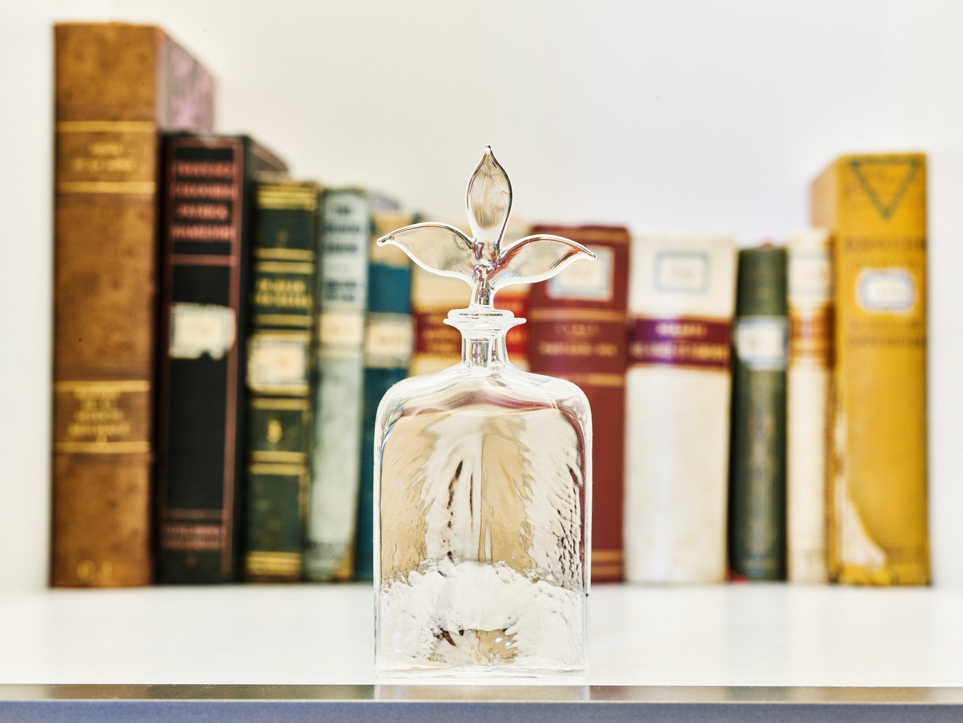 Glass bottle and books in the background inside Classic Suite at Hotel Eden, Rome
