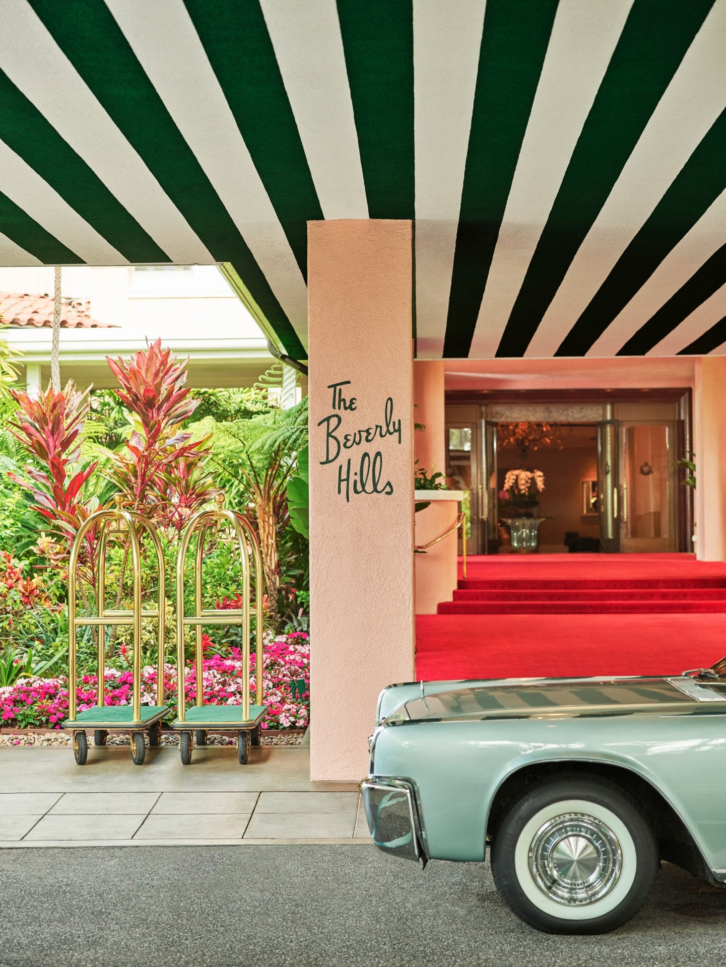 The Beverly Hills Hotel red carpet entrance with car and bellman carts. 