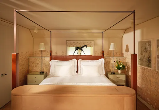 Four-poster bed with equestrian artwork in the Stable Junior Suite at Coworth Park in Ascot