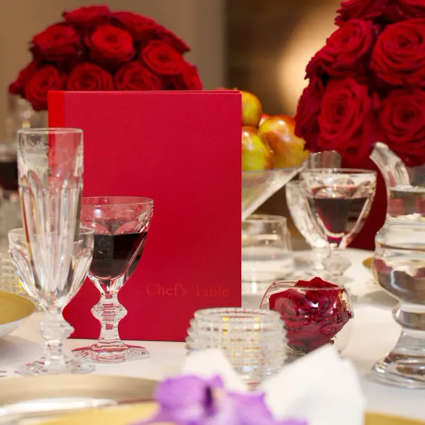 Chef's Table detail white roses, champagne flutes, dinner setup