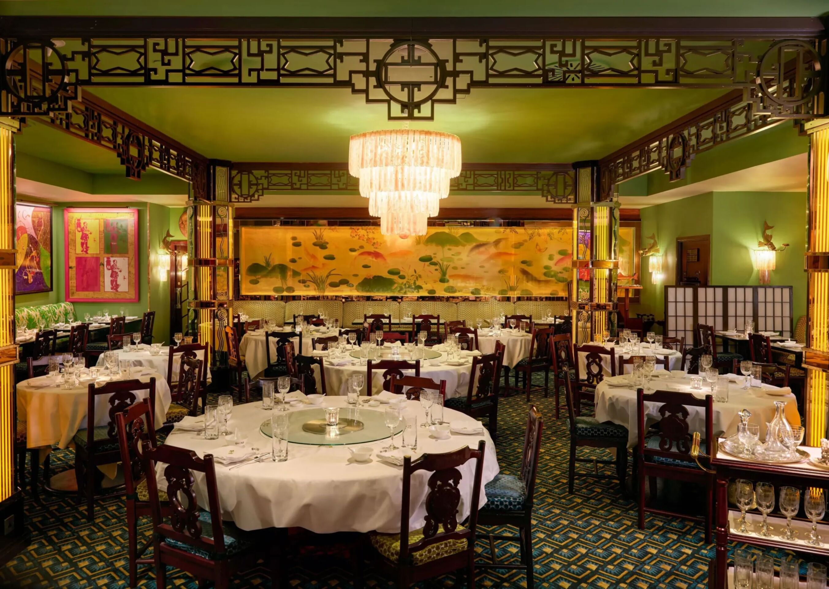 Main dining room at China Tang at The Dorchester, featuring round banquet tables, a statement chandelier and a panoramic Chinese-inspired mural.
