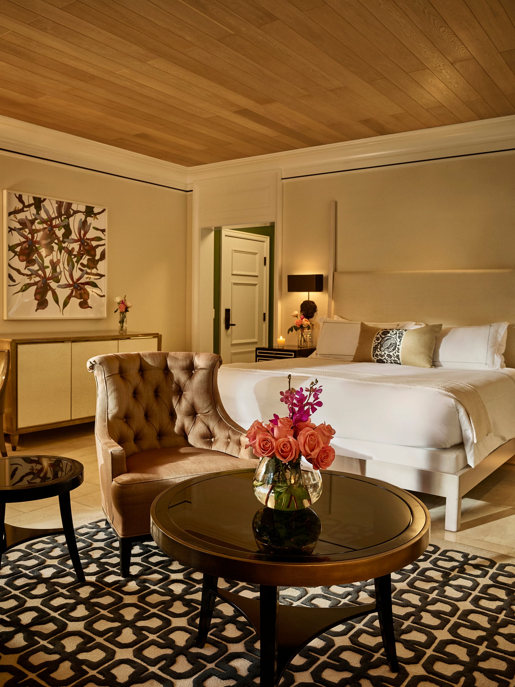 Junior suite at Hotel Bel-Air highlighting the sitting area with a small table and bouquet of flowers perched in front of the king size bed. 