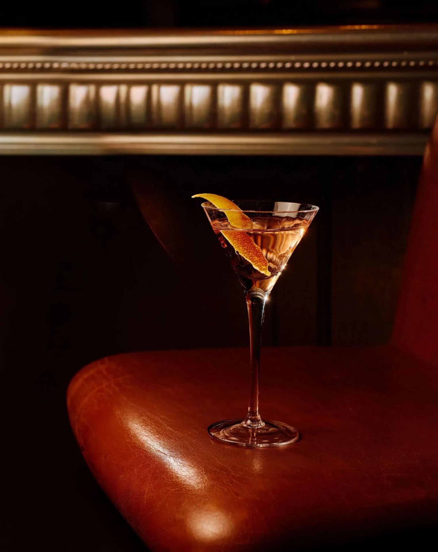 Signature Martini at The Grill at The Dorchester, elegantly presented in a classic stemmed glass and garnished with a lemon twist, set against the restaurant's warm leather seating and ambient lighting.