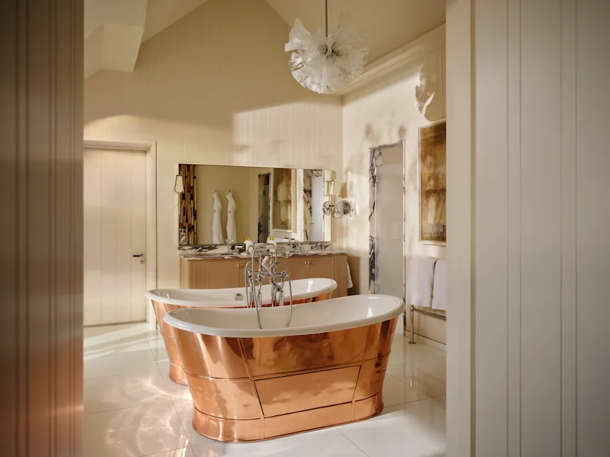 Freestanding copper bathtub with mirrored surround in the Fairway Stable Premium Suite
