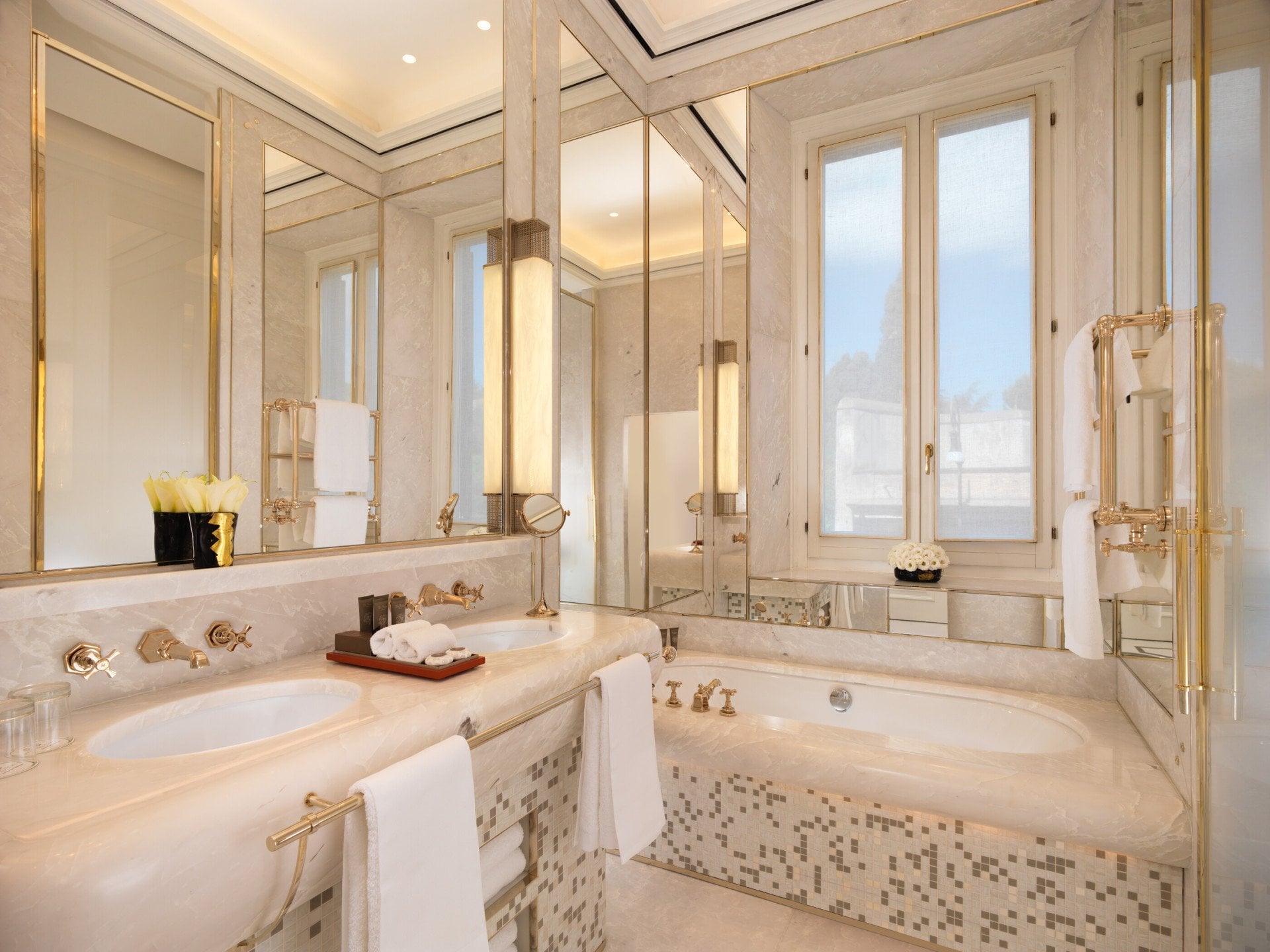 White marble bathroom of classic room with double sinks and bathtub at Hotel Eden, Rome