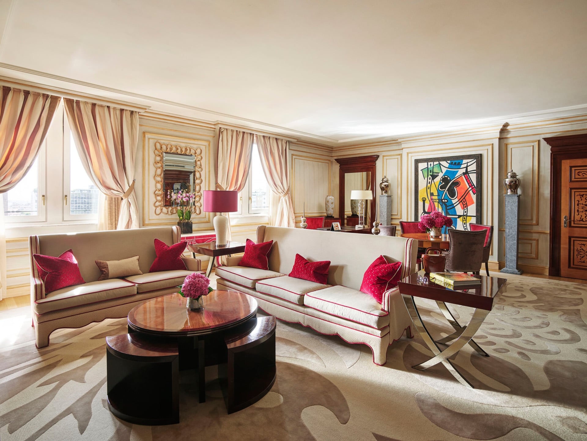 Imperial Executive Suite Living Room furnished with white sofas in the foreground and colourful art pieces in the background 