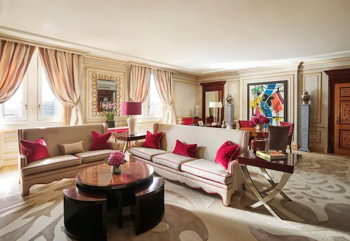 Imperial Executive Suite Living Room furnished with white sofas in the foreground and colourful art pieces in the background